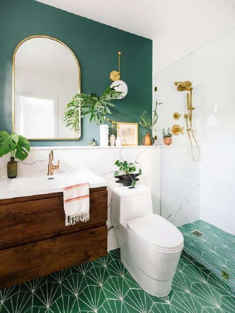 38. Decoração de banheiro verde e branco com gabinete de madeira e arandela dourada – Foto: Casa de Valentina