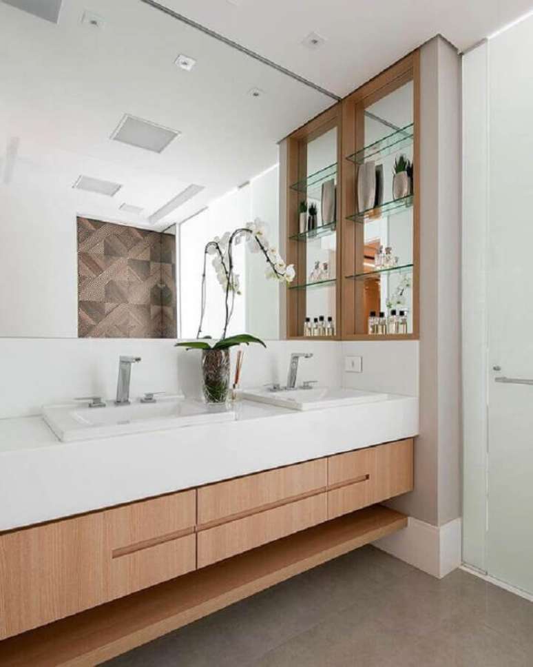 9. Bancada planejada para decoração de banheiro com nicho de madeira e prateleiras de vidro – Foto: Decor Salteado