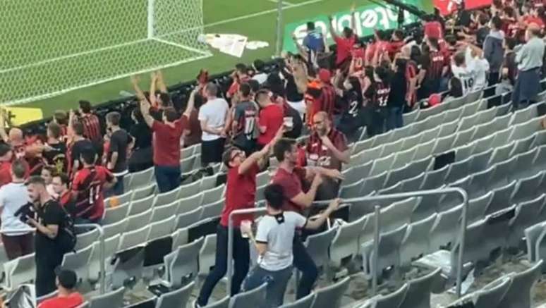 Torcedores do Athletico-PR passam a mão no braço para mostrar pele branca para a torcida do Atlético-MG