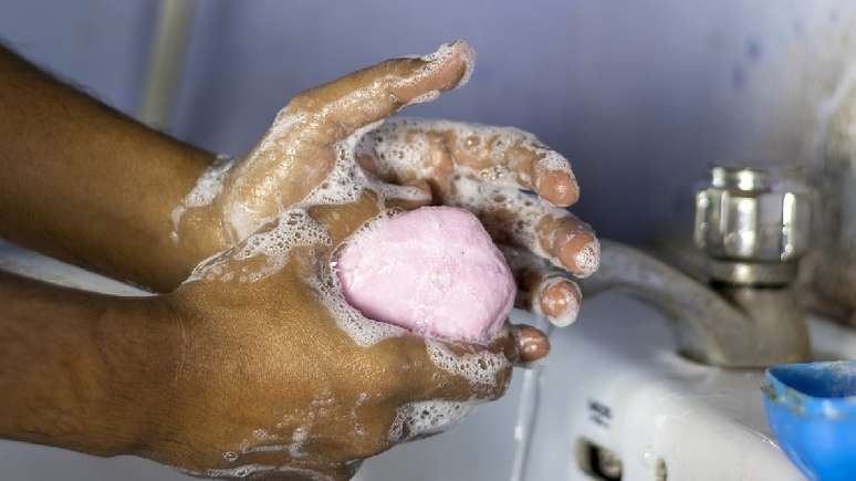 Pessoa, com acesso ao saneamento, lava suas mãos com água e sabão