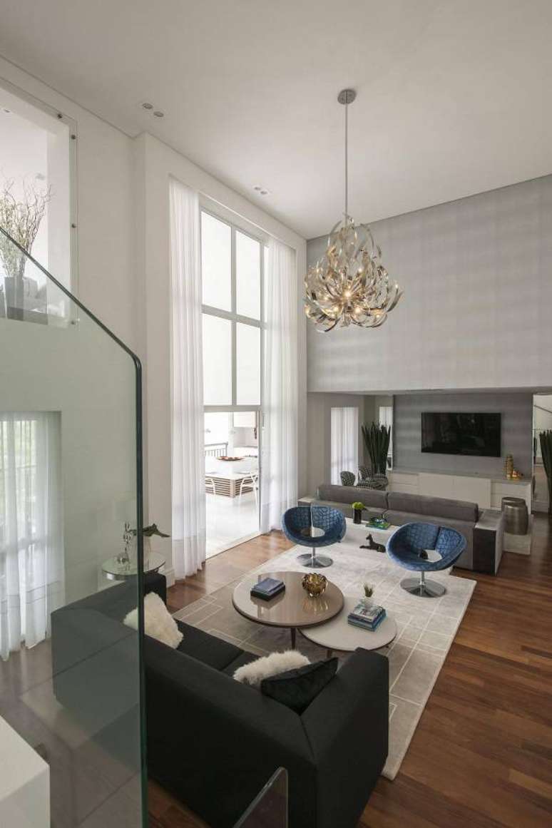 2. Sala com p&eacute; direito alto e cortina branca nas portas de vidro &ndash; Foto Erica Salguero