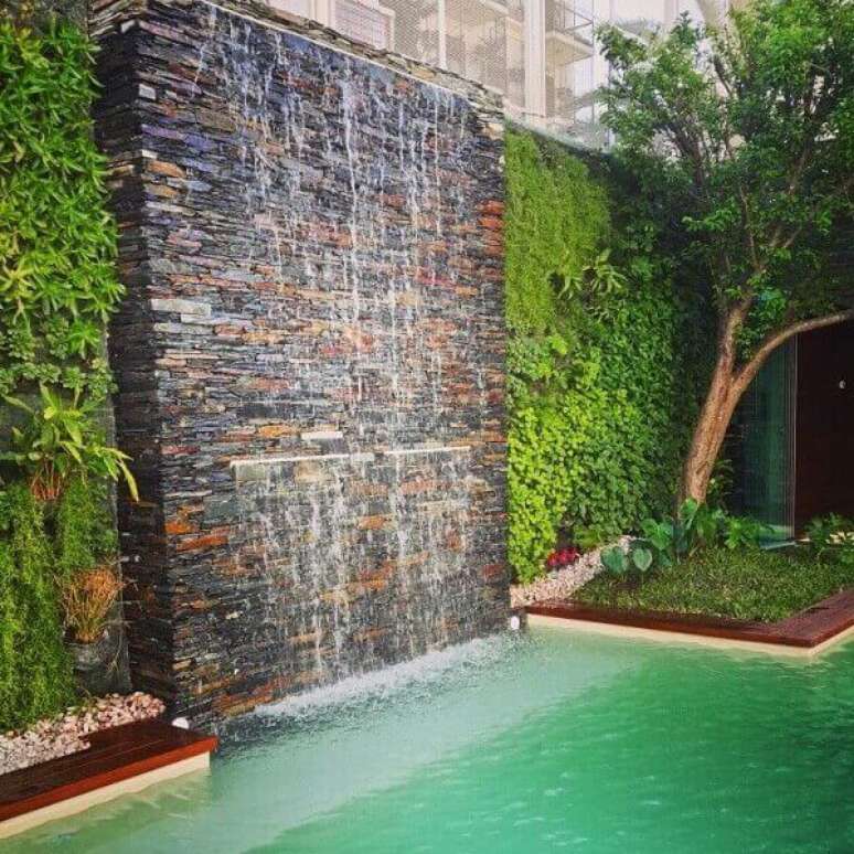 46- A cascata para piscina em parede de pedra tem duas saídas de água com alturas diferentes. Fonte : Pinterest
