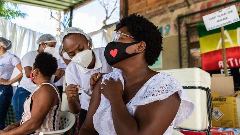 A foto mostra uma mulher quilombola sendo vacinada.
