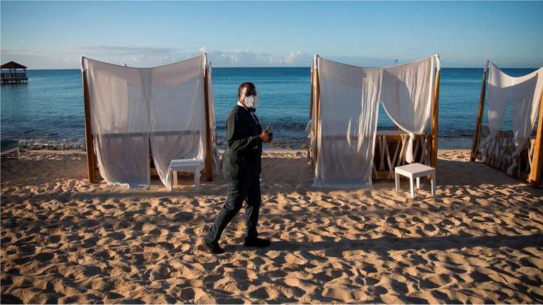 Trabalhador com máscara em uma praia deserta