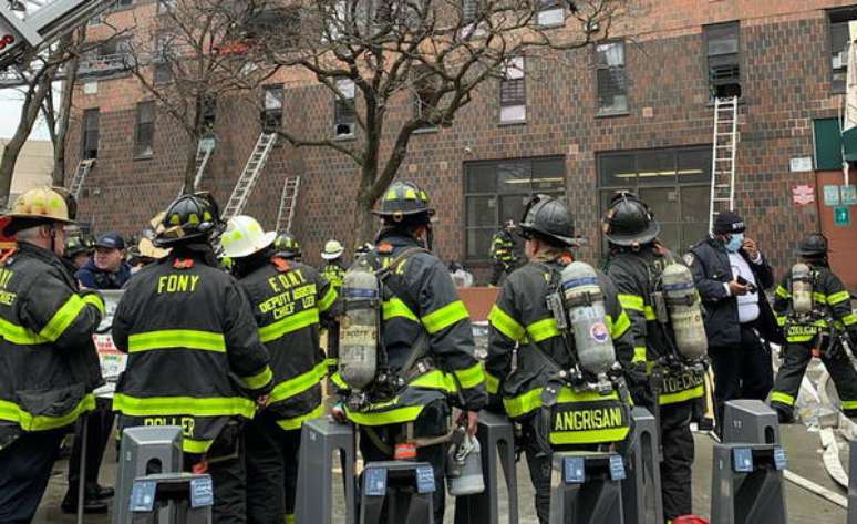 Homens do Corpo de Bombeiros em frente ao prédio atingido pelo incêndio