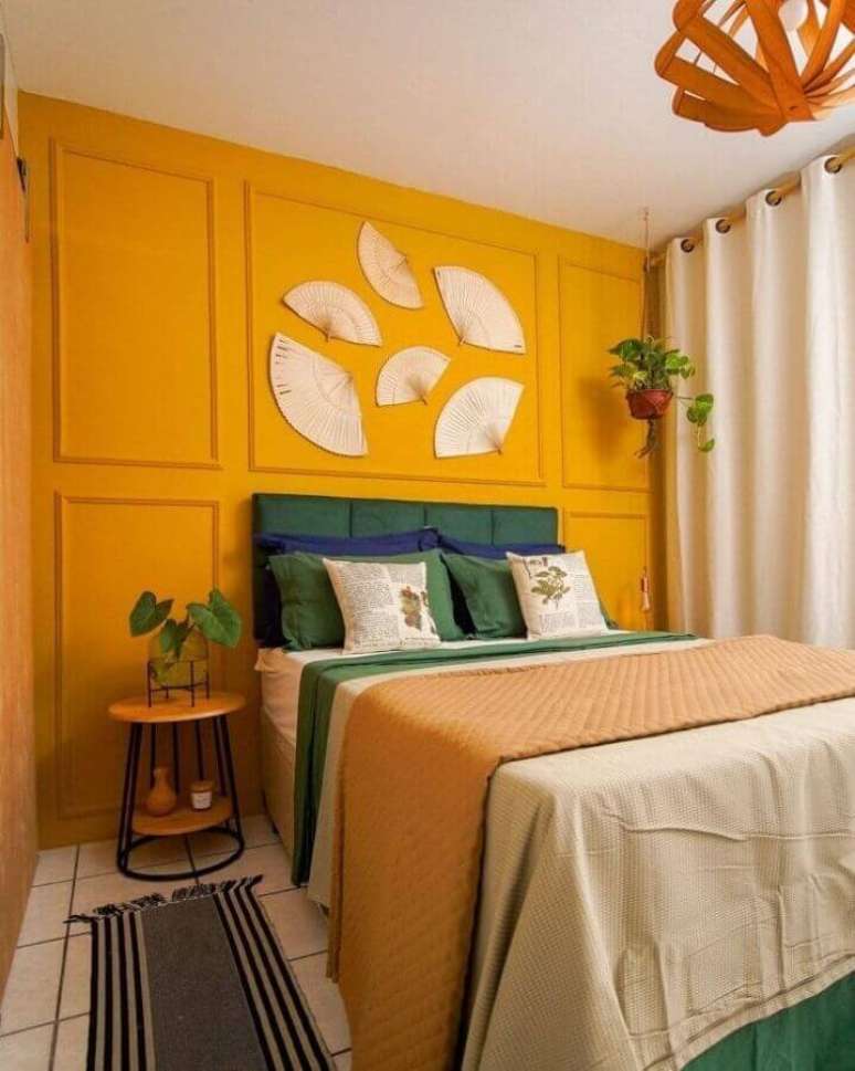 57. Moldura boiserie para quarto decorado com parede amarela e mesa lateral redonda – Foto: Karla Amadori