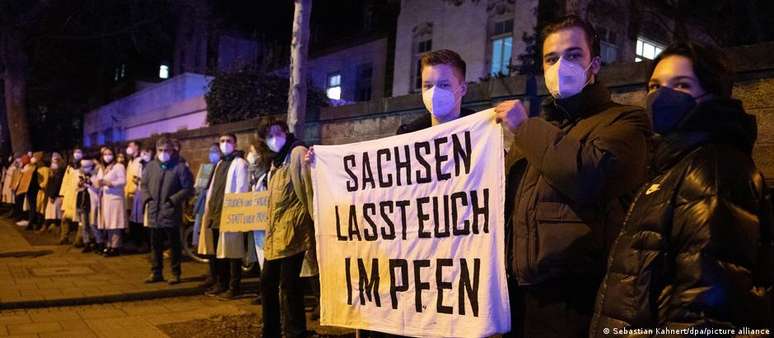 Barreira humana formada por estudantes em frente à clínica em Dresden. Faixa com os dizerem "Saxônia, vacine-se"