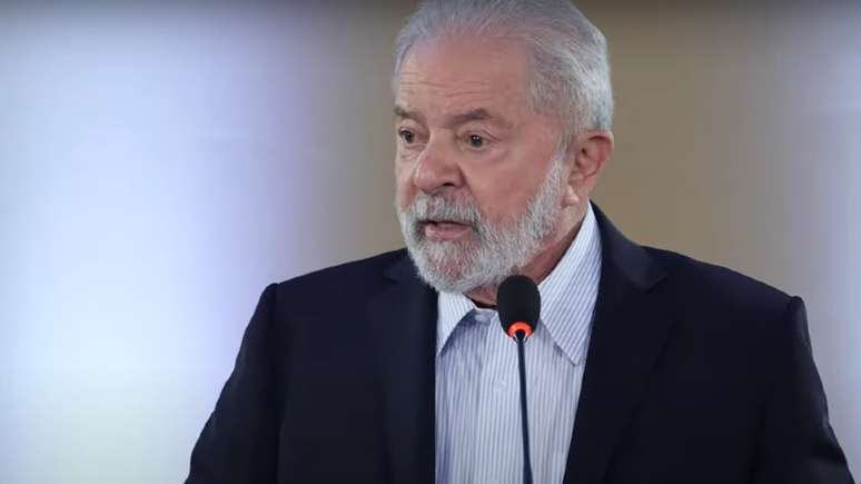 A imagem mostra o ex-presidente Luis Inácio Lula da Silva. Ele veste uma camisa azul claro e um paletó preto