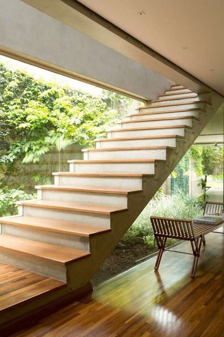 27. Jardim embaixo da escada com banco de madeira e parede de vidro – Foto Decor Facil
