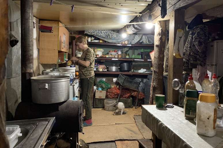 Um soldado ucraniano prepara comida em uma cozinha improvisada perto da linha de frente