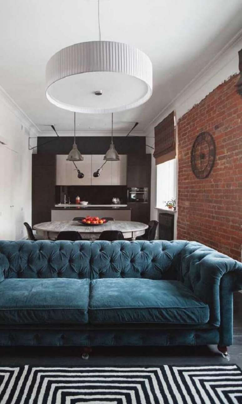 58. Sof&aacute; capiton&ecirc; antigo azul e parede de tijolinho se destacam na decora&ccedil;&atilde;o. Fonte: Decor F&aacute;cil