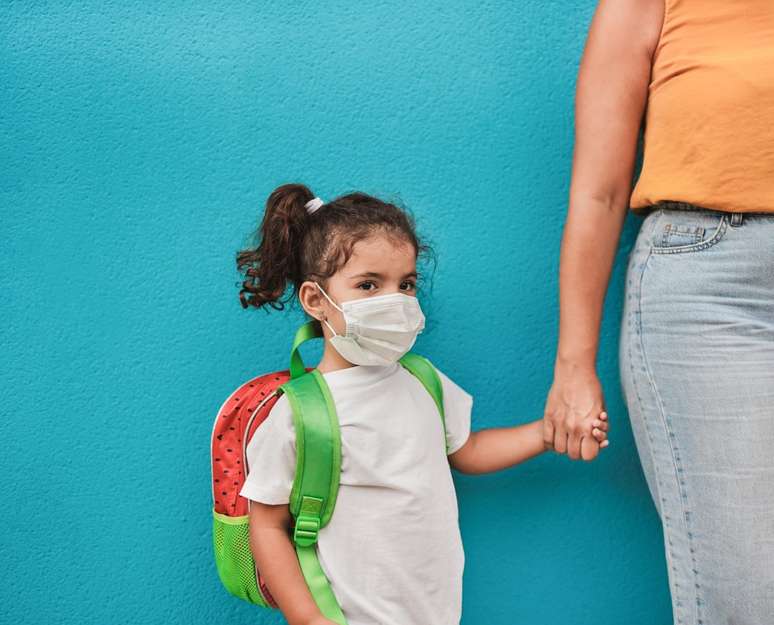 menina com mochila na frente de parede azul
