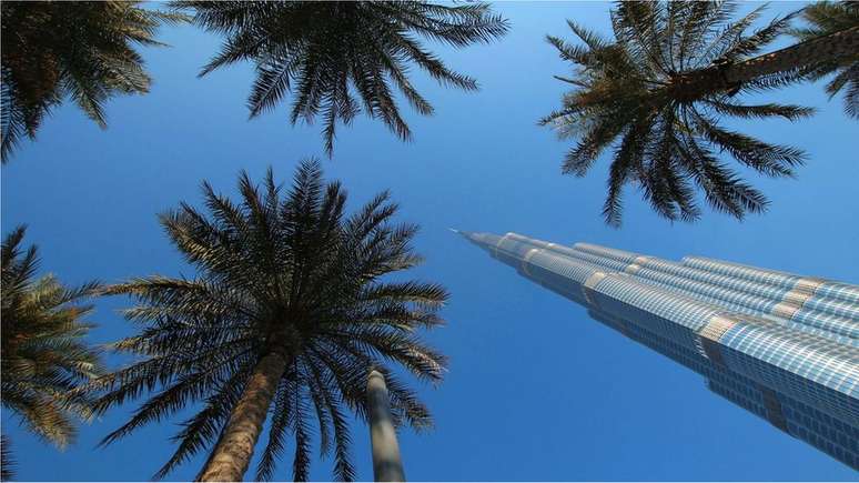 O arranha-céu Burj Khalifa de Dubai contrasta com as tamareiras em sua base