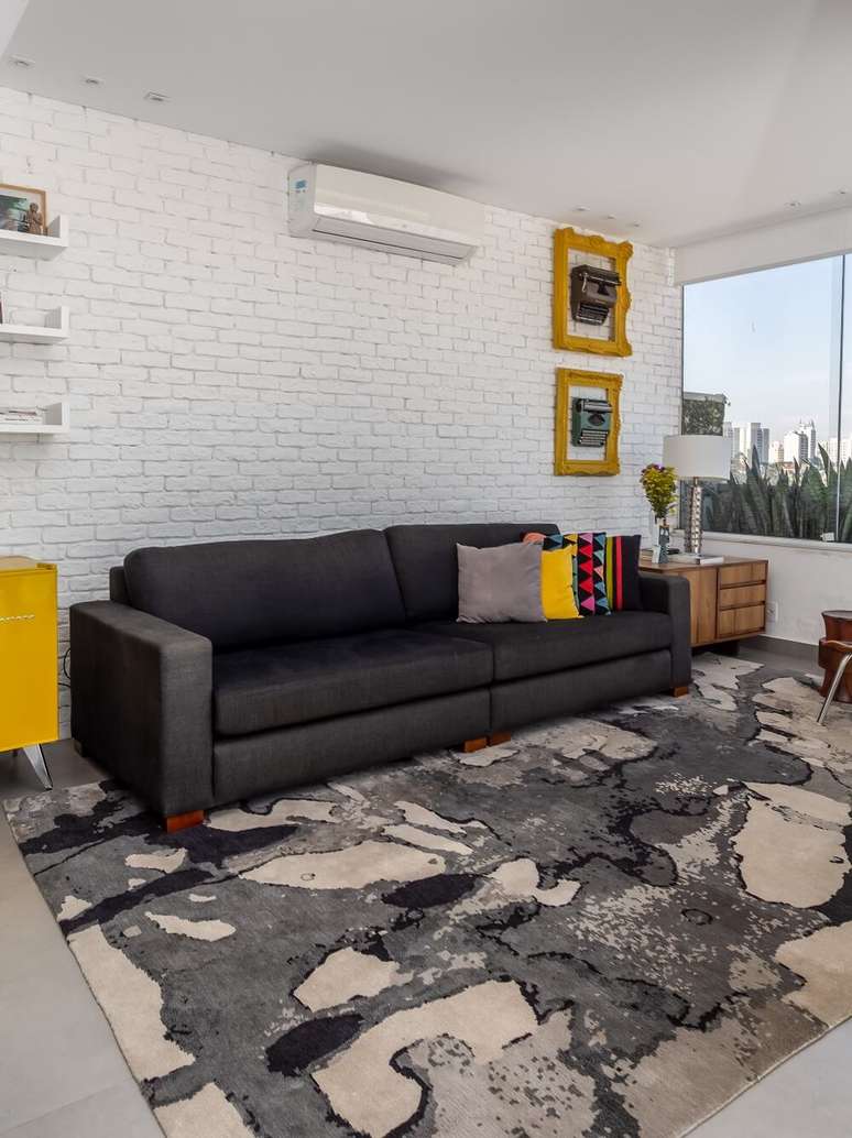 12. A parede de tijolinho branco, o sof&aacute; cinza e o tapete formam uma combina&ccedil;&atilde;o neutra no ambiente. Foto: JP Image