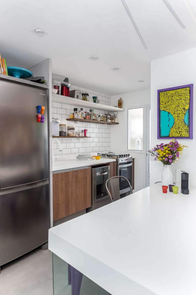 7. Arm&aacute;rios em padr&atilde;o madeira, tampo de Corian branco e cer&acirc;mica estilo azulejo de metr&ocirc; revestem a parede. Foto: JP Image