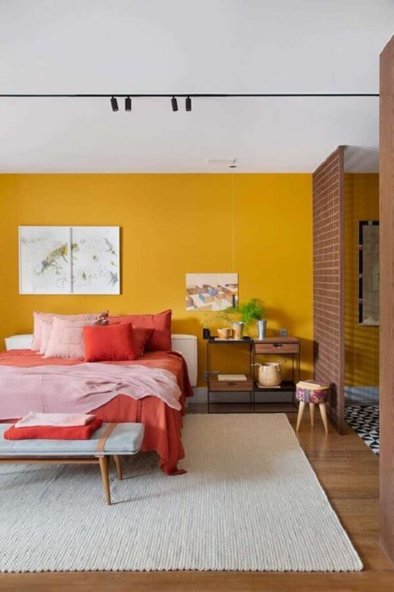 2. Cores da natureza para decora&ccedil;&atilde;o de quarto de casal com parede amarela e jogo de cama terracota &ndash; Foto: MCA Est&uacute;dio