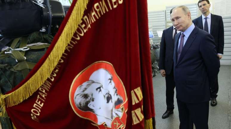 Presidente russo Vladimir Putin observa bandeira com retratos dos líderes soviéticos Vladimir Lenin e Joseph Stalin (foto de 06/03/2020)