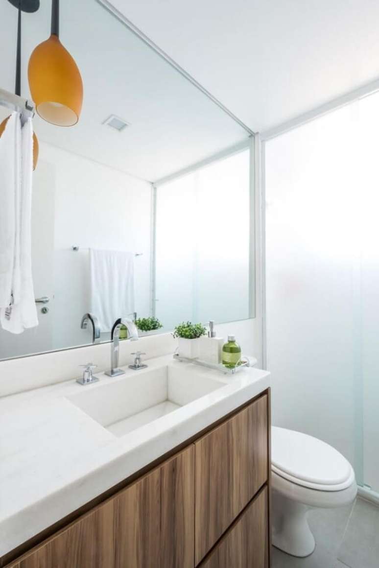 13. Pendente laranja e gabinete para banheiro pequeno com cuba branca. Fonte: SP Estudio