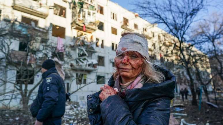 Mulher fica ferida em explosão de edifício durante ofensiva militar russa em Chuguiv, no leste da Ucrânia, na manhã de 24/2