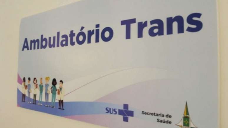 Imagem mostra a porta de uma sala de consultório médico. Há uma placa escrito "Ambulatório Trans".