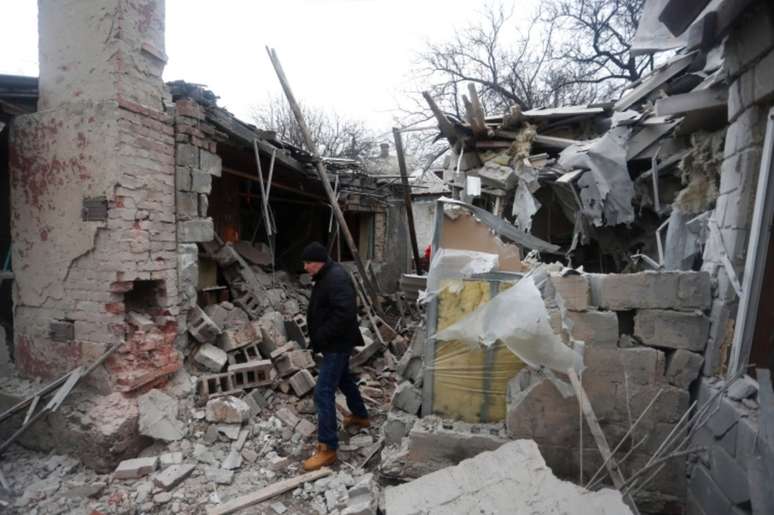 Um homem caminha em meio aos escombros de prédios que moradores disseram terem sido destruídos por bombardeios na cidade de Donetsk