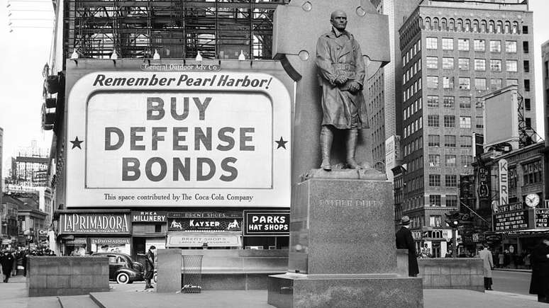 Propaganda na Times Square em 1940 diz "compre t&iacute;tulos de defesa"