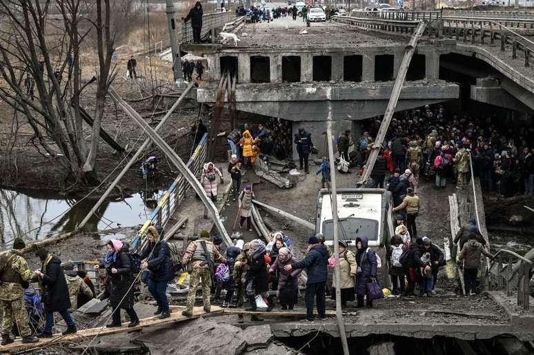 Pessoas atravessam uma ponte destruída durante evacuação da cidade de Irpin, no dia 5 de março de 2022