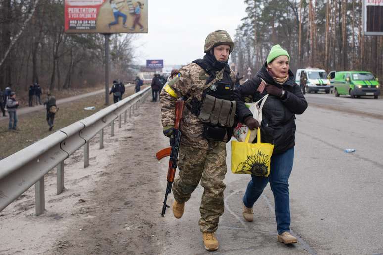 Militar ucraniano ajuda mulher a fugir de região sob ataque russo; símbolo adicionado por ele ao uniforme chamou a atenção nas redes sociais por ser associado ao nazismo