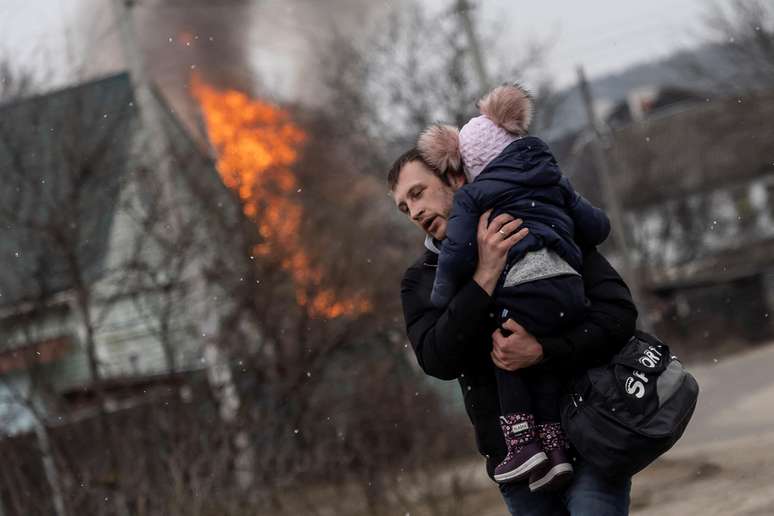 Homem e criança fogem de bombardeios em Irpin, na Ucrânia 