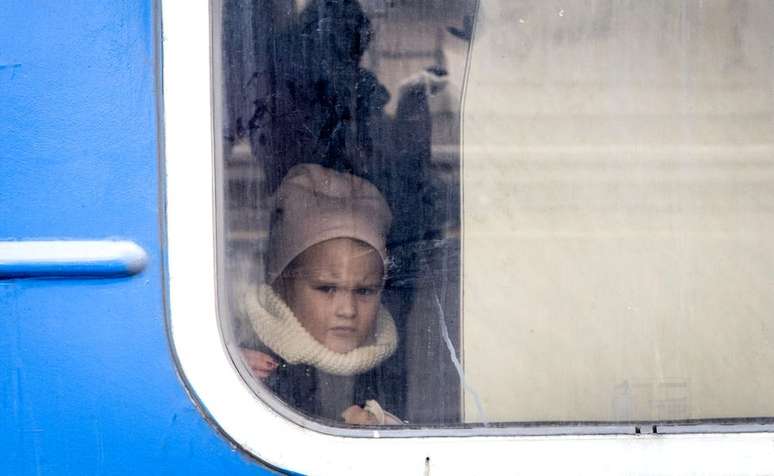 Menina na janela de um trem que saiu carregado de mulheres e crianças que fugiram dos combates em Bucha e Irpin no dia 4 de março de 2022