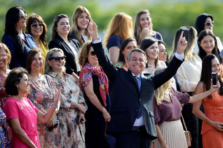 O presidente Jair Bolsonaro faz gestos enquanto participa de cerim&ocirc;nia de hasteamento da bandeira nacional com convidadas em frente ao Pal&aacute;cio da Alvorada, em Bras&iacute;lia