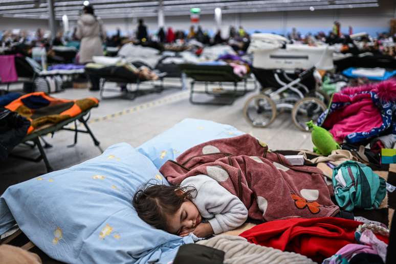 Antes de chegarem a Polônia, famílias aguardam em abrigos temporários para refugiados na fronteira, como este feito em um supermercado anteriormente abandonado.