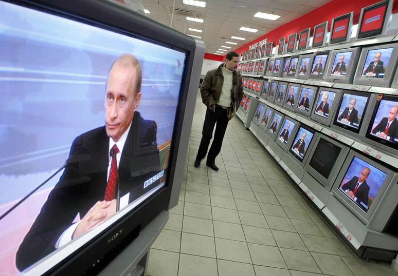 Em foto de 2006, aparelhos de TV transmitem coletiva de imprensa anual de Putin