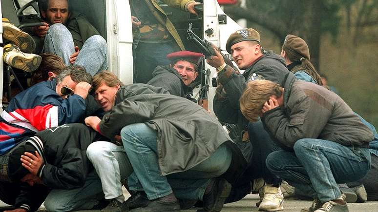 Um soldado das forças especiais da Bósnia e civis sob fogo de franco-atiradores sérvios, em Sarajevo, 6 de abril de 1992