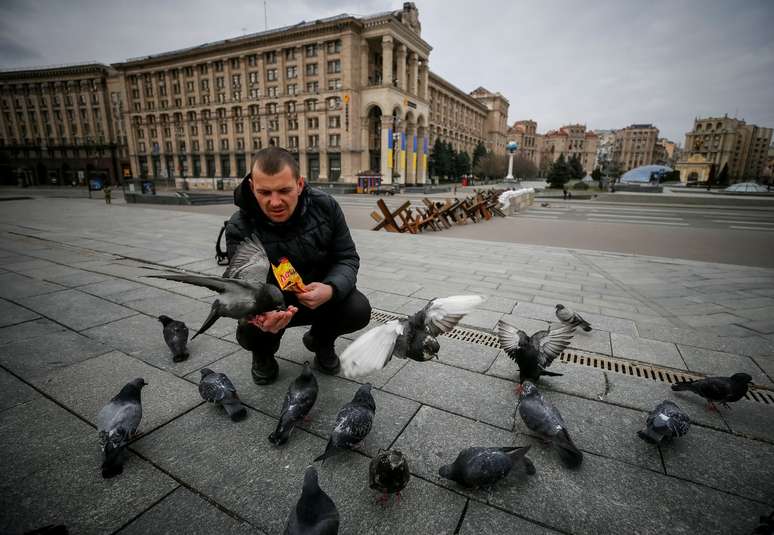 Homem alimenta pombos em Kiev, na Ucr&acirc;nia