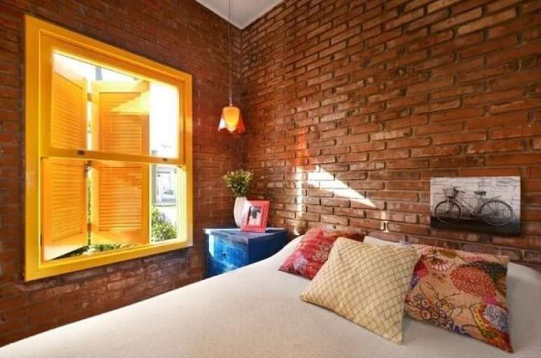 34. Quarto de casal com m&oacute;veis usados pintado de azul ao lado da cama combinado com a parede de tijolinhos r&uacute;stica. Projeto de Arquitetando Ideias