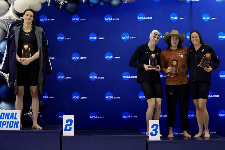 Foto mostra a nadadora transgênero Lia Thomas no topo pódio sozinha enquanto as demais medalhistas — Emma Weyant, Erica Sullivan e Brooke Forde — posam juntas