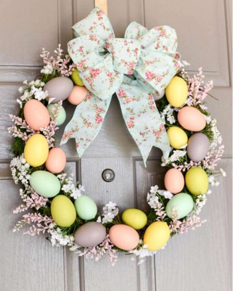 35. Enfeites de P&aacute;scoa para porta com guirlanda feita com v&aacute;rios ovinhos coloridos e la&ccedil;o floral &ndash; Foto: Simply Easter