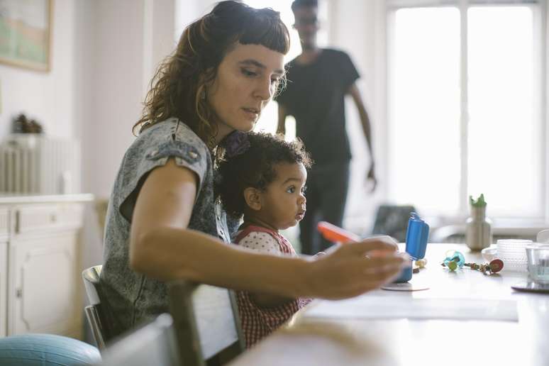 Mãe-trabalhando-com-a-filha-no-colo-em-casa