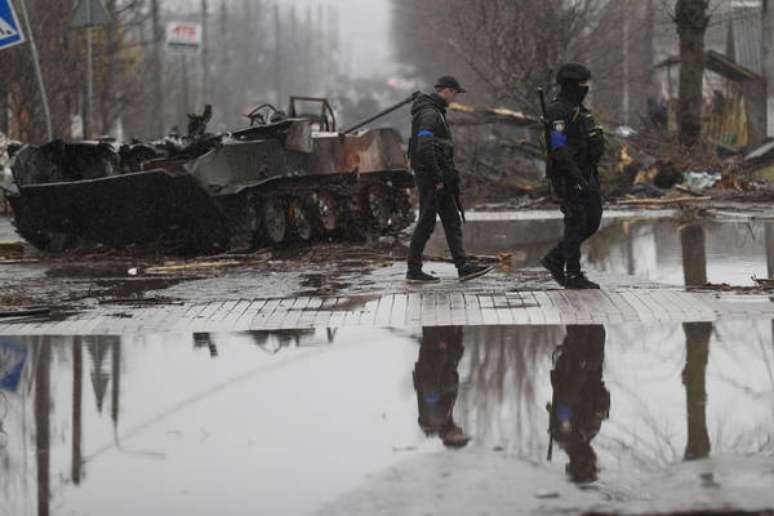 Soldados ucranianos inspecionam ve&iacute;culo russo destru&iacute;do em Bucha, nos arredores de Kiev