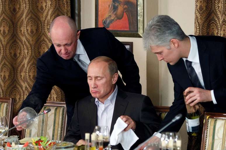 Uma foto de novembro de 2011 mostra Yevgeny Prigozhin (E) auxiliando Vladimir Putin em um banquete perto de Moscou