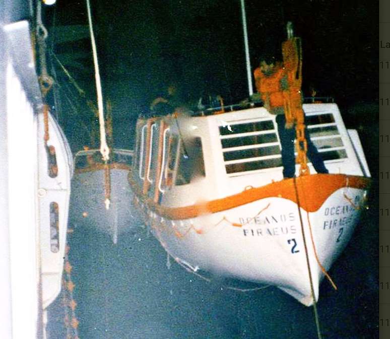 Um dos tripulantes filipinos que permaneceram a bordo tentando baixar um bote salva-vidas pendurado a bombordo do navio