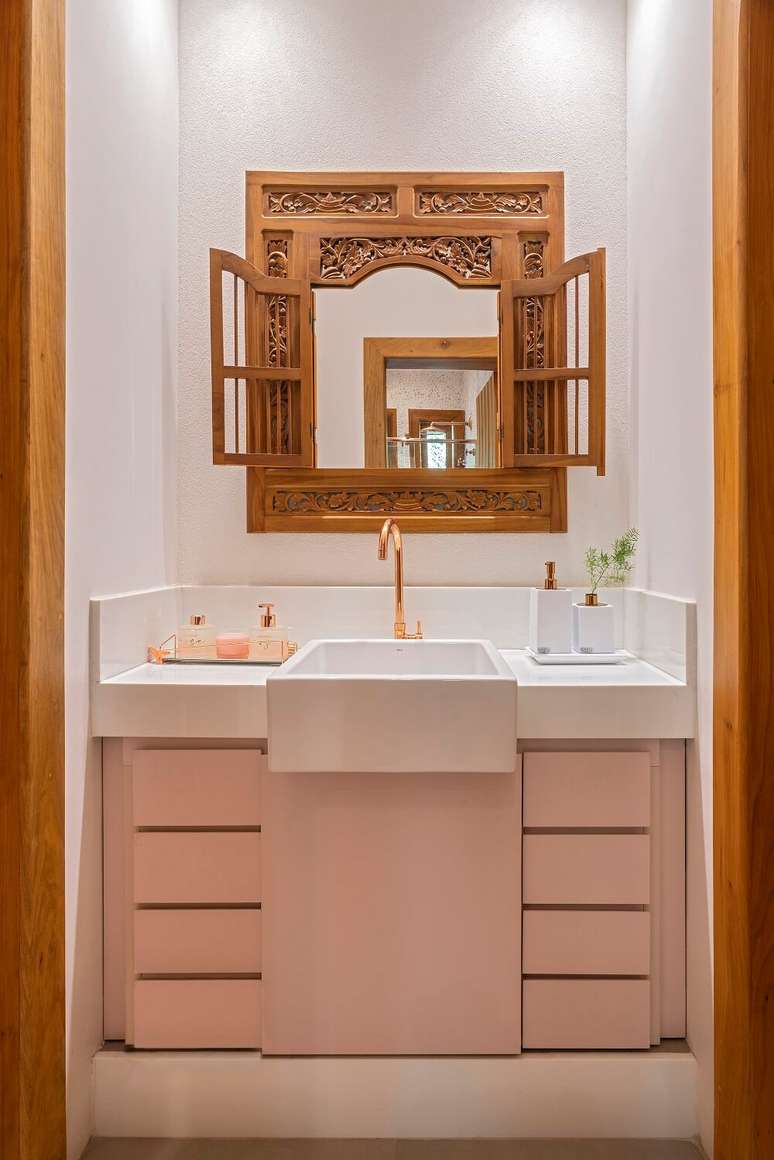 16. Espelho decorativo com formato de janela e arm&aacute;rio de banheiro em tom rosa. Foto: Daniel Mansur Fotografia