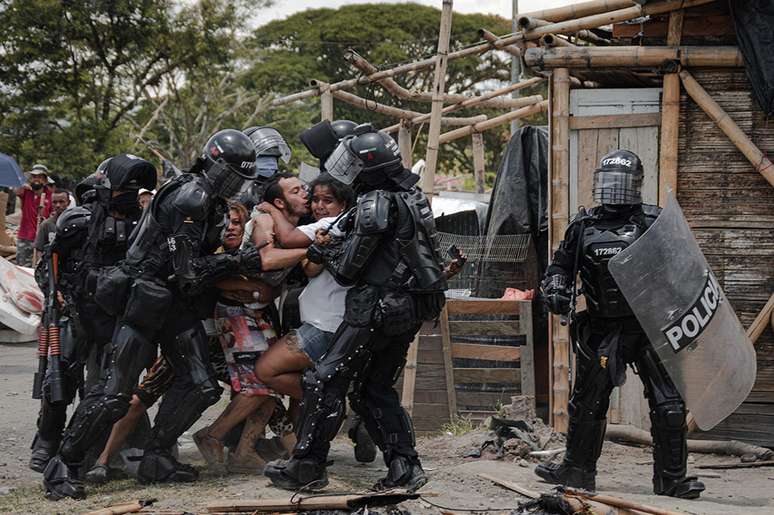 Policiais prendem um homem enquanto sua esposa e família resistem, durante despejos de pessoas do assentamento de San Isidro, em Puerto Caldas, Risaralda, Colômbia, em 6 de março de 2021