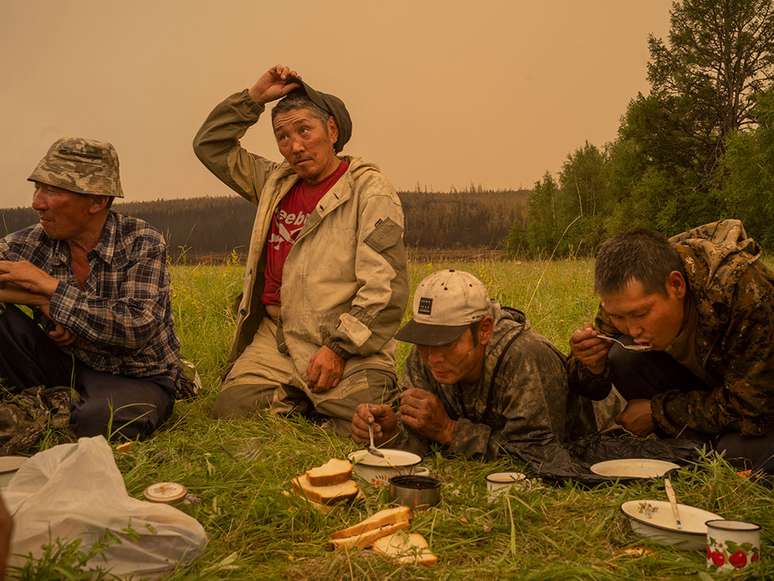 Voluntários locais de combate a incêndios fazem uma pausa para comer em um campo em Magaras, Sakha central, Sibéria, Rússia, em 1º de julho de 2021