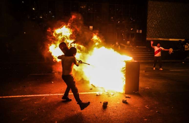 Um manifestante tenta apagar um incêndio em frente à sede do Supremo Tribunal Federal, em Lima, em 5/4