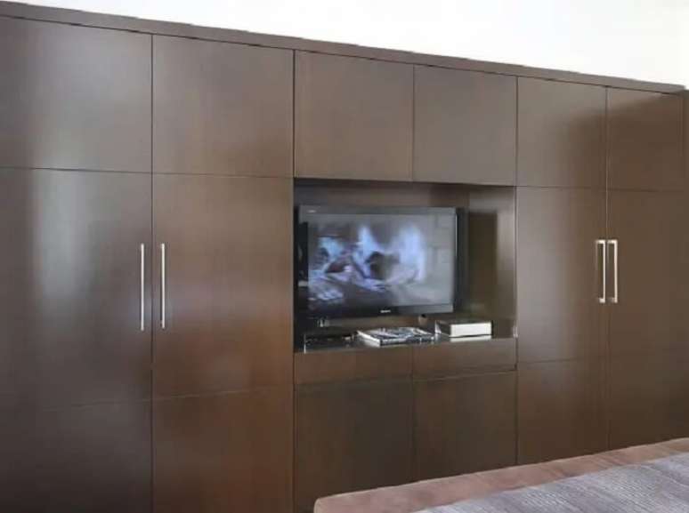 26. Guarda roupa com madeira escura acomoda a tv no quarto. Fonte: Carolina Ouro