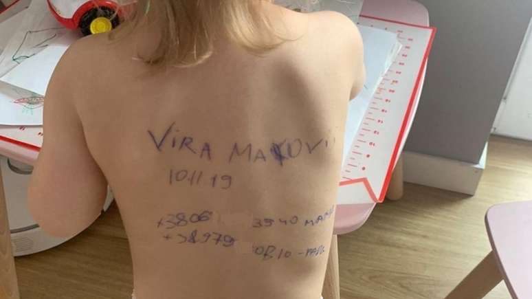 Imagem mostra as costas de Vira com mensagem com nome dela, data de nascimento e telefones