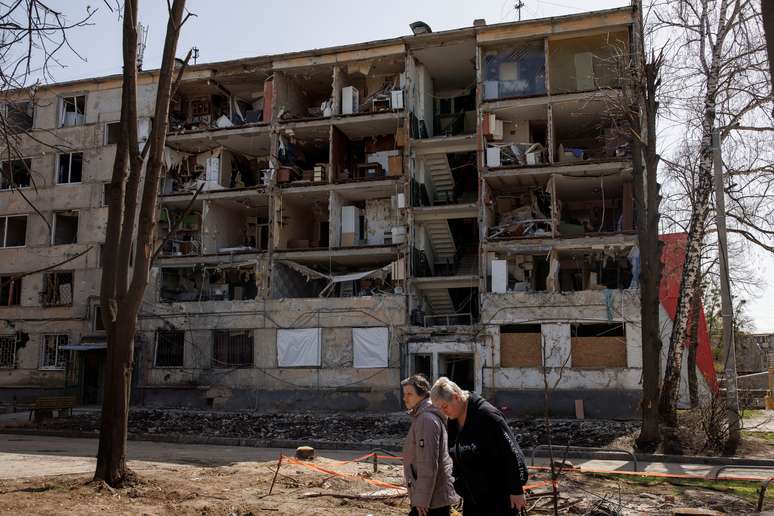 Mulheres passam por prédio destruído pela guerra na cidade de Kharkiv
