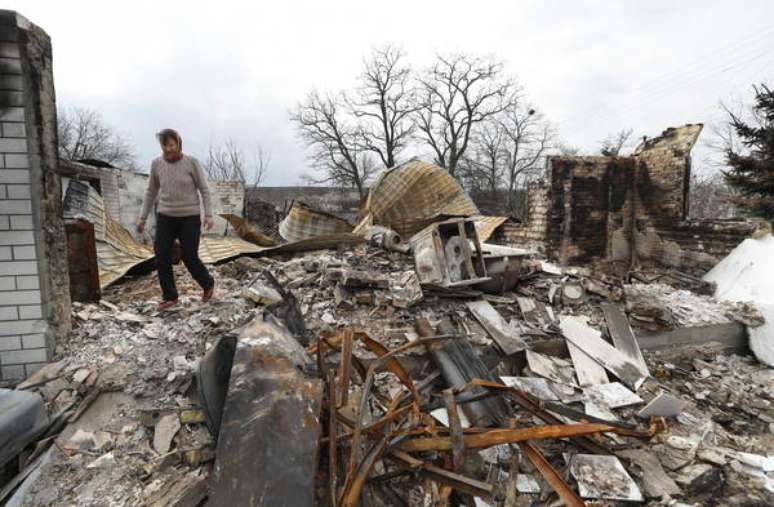 Homem caminha sobre escombros de construção destruída por bombardeio russo em Rusaniv, arredores de Kiev